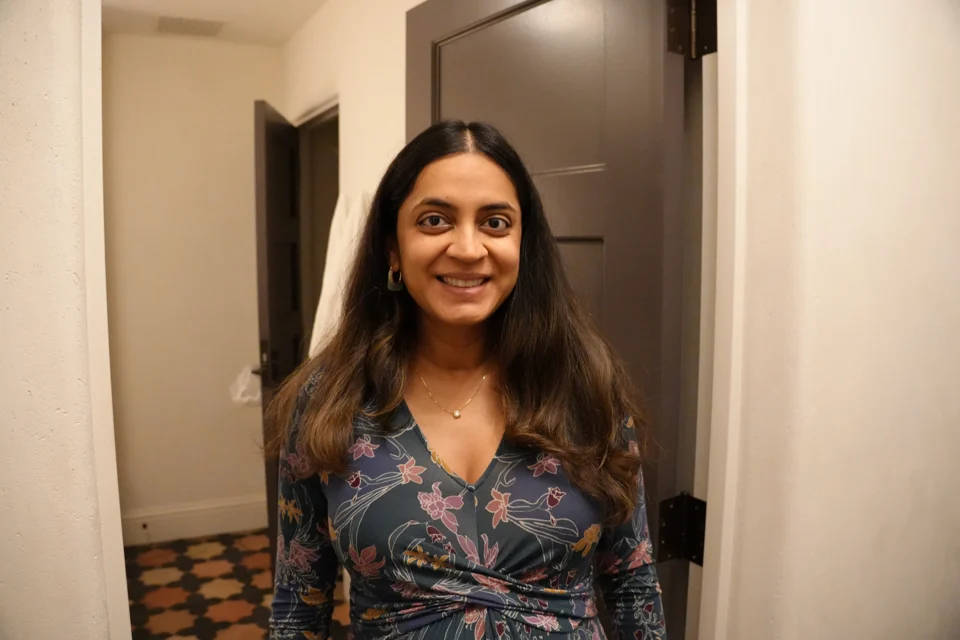 Mital in a floral dress in the mansion hallway